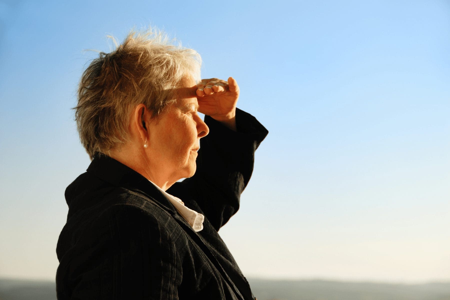 woman covering her eyes from sun, looking out at landscape illustrating commercial property insurance market outlook