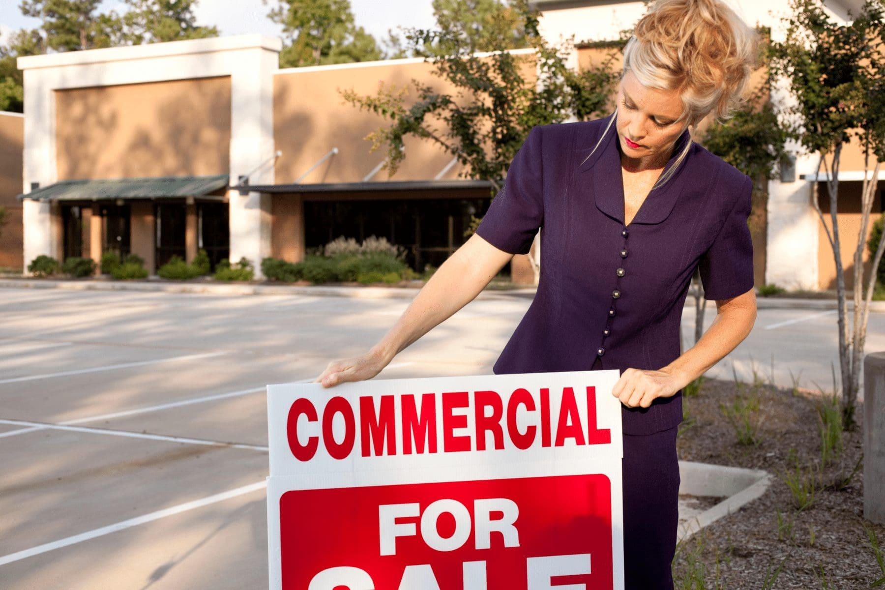 a real estate woman putting up a for sale sign for a commercial property with inflation guard